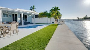 Ein modernes Haus mit Pool, Gartenmöbeln und Blick auf das Wasser.