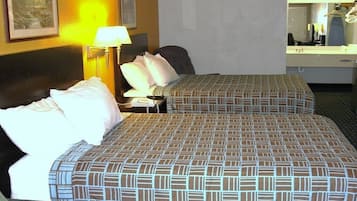 Une chambre d’hôtel avec deux lits, une table de chevet, une lampe, une chaise, un bureau et un miroir.