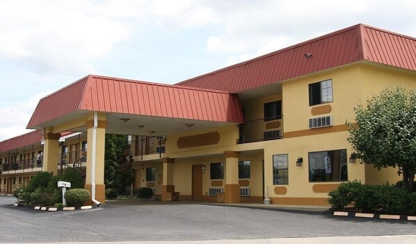 A hotel with a red roof, yellow walls, and a covered entrance.