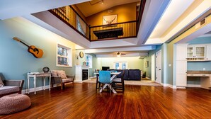 A spacious living area with hardwood flooring, a dining table, and chairs. A guitar is mounted on the wall. - IU Getaway | Hot Tub, Fire Pit & 10 Min to Campus 3BR, 3BA (Bloomington)