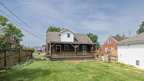 A residential property with a fenced backyard, a wooden deck, and a brick house with a gabled roof. - OPEN 4BR/2BA • Sleeps 8 • Near Hwy • Covered Deck • Close to Downtown & Expo Ctr (Louisville)