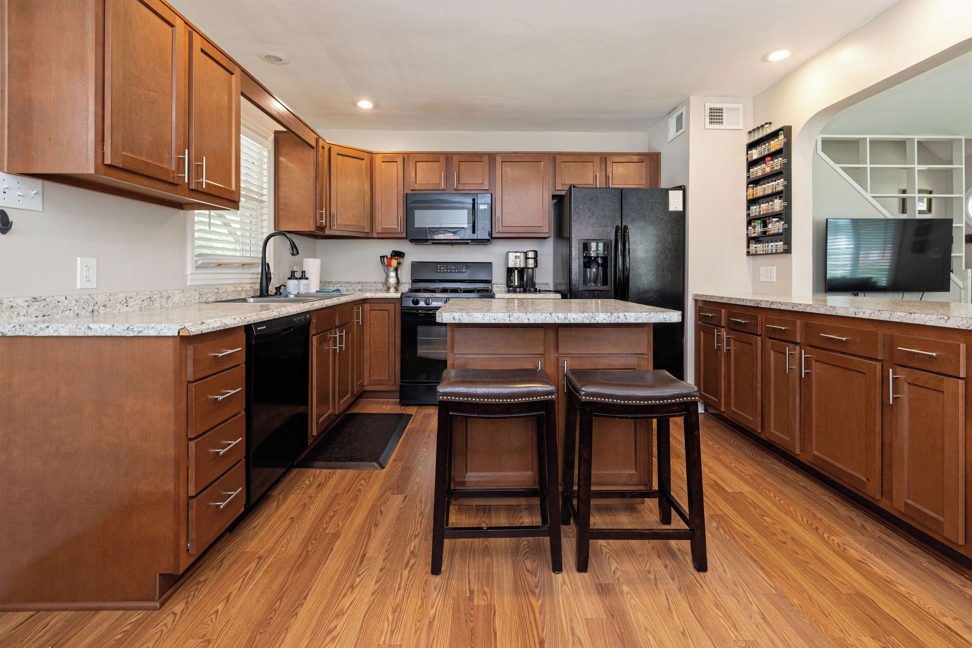 A kitchen with wooden cabinets, a granite countertop, a stainless steel refrigerator, a microwave, and a coffee maker.