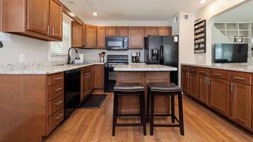 A kitchen with wooden cabinets, a granite countertop, a stainless steel refrigerator, a microwave, and a coffee maker.