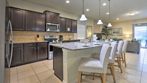 Una cocina moderna con gabinetes oscuros, encimera de granito y una isla central con taburetes.