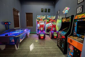 A room with a pool table, arcade games, and a billiards machine.
