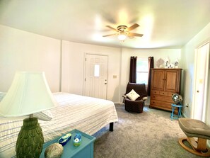 Une chambre à coucher avec un lit, une chaise, une armoire et un ventilateur de plafond.