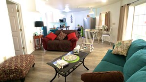 A living room with a sofa, a rocking chair, a coffee table, and a patterned ottoman. - ❤️Amazing Round House, Ground Floor Unit, Easy Walk To The Beach, Self Check-In (Carolina Beach)