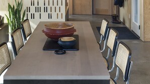 A modern dining area with a long table, chairs, and a decorative wall panel.
