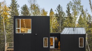 A modern cabin with a large window, a door labeled "GREEN," and a small porch area.