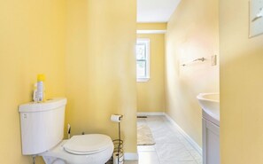 Een badkamer met een toilet, een wastafel en een raam.