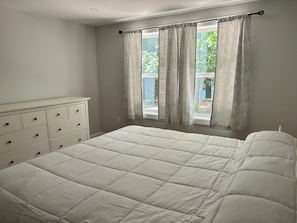 Een slaapkamer met een bed, een kaptafel en een raam met gordijnen.