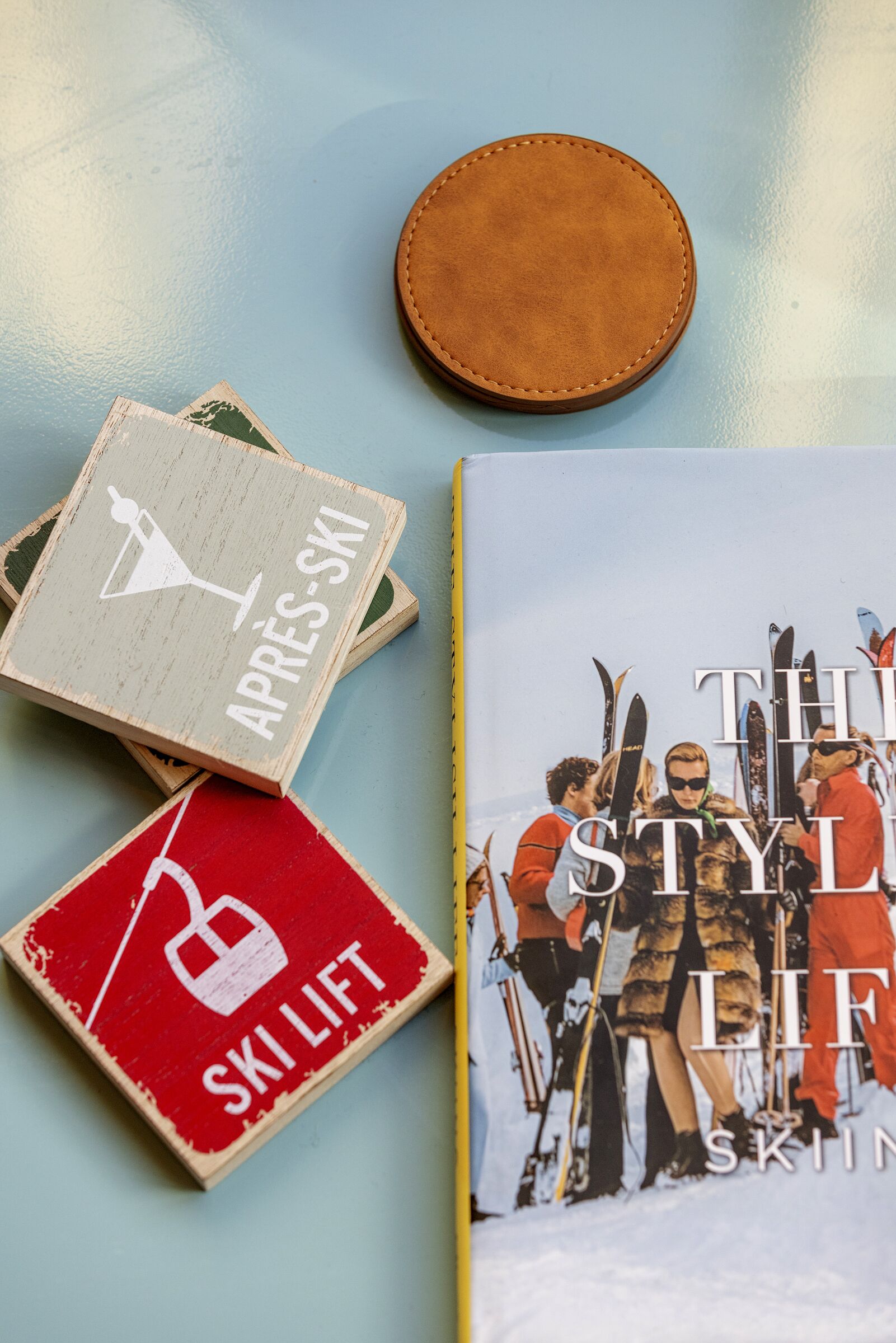 A book titled "THE STYLE OF SKIING" and two wooden coasters with ski-related symbols.