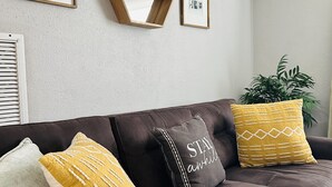 A dark brown sofa with three decorative pillows, a wall-mounted mirror, and framed pictures. - House near Tarpon Springs Beaches and Weeki Wachee Springs (Holiday)