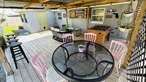 A covered patio with a round table, pink chairs, and a foosball table. - House near Tarpon Springs Beaches and Weeki Wachee Springs (Holiday)