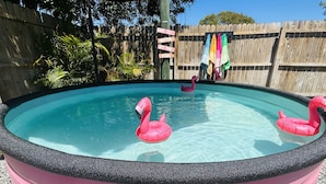 A swimming pool with pink flamingo floats and a wooden fence in the background. - House near Tarpon Springs Beaches and Weeki Wachee Springs (Holiday)