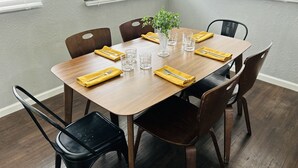 A dining table set with yellow napkins, cutlery, and glasses, surrounded by wooden chairs in a room with wooden flooring and a grey textured wall. - House near Tarpon Springs Beaches and Weeki Wachee Springs (Holiday)