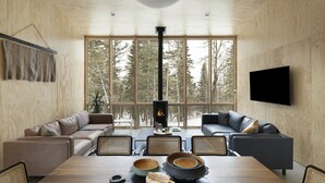 A modern living room with a large wooden table, sofas, and a fireplace. - Scandinavian Chalet and sauna in Lutsen - Grey (Lutsen)