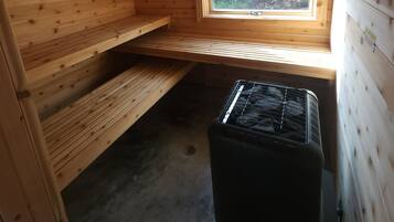 Une petite cabane en bois, avec un toit en pente, une fenêtre et un radiateur noir.
