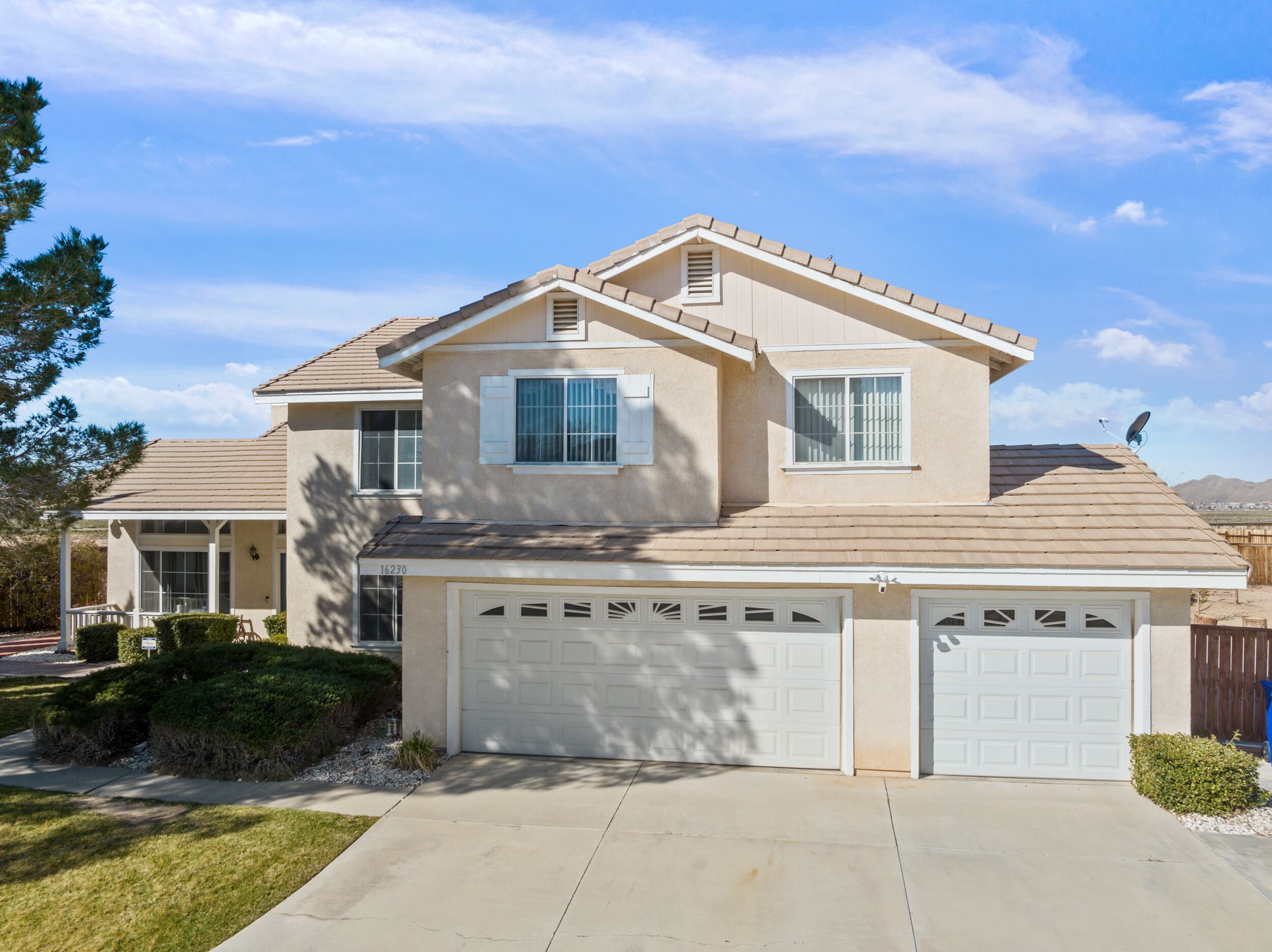 A two-story house with a garage, a covered porch, and a satellite dish.