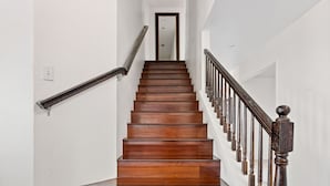 Una scala in legno con un corrimano a sinistra e una ringhiera a destra, che conduce a un ingresso in alto.