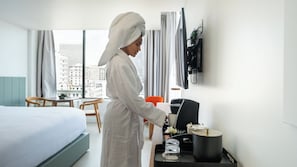 A hotel room with a bed, a desk with a coffee maker, a chair, and a TV on the wall. - Dayton Vitality Hotel (Dayton)