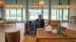 A spacious lobby with large windows, wicker furniture, and hanging wicker lamps.