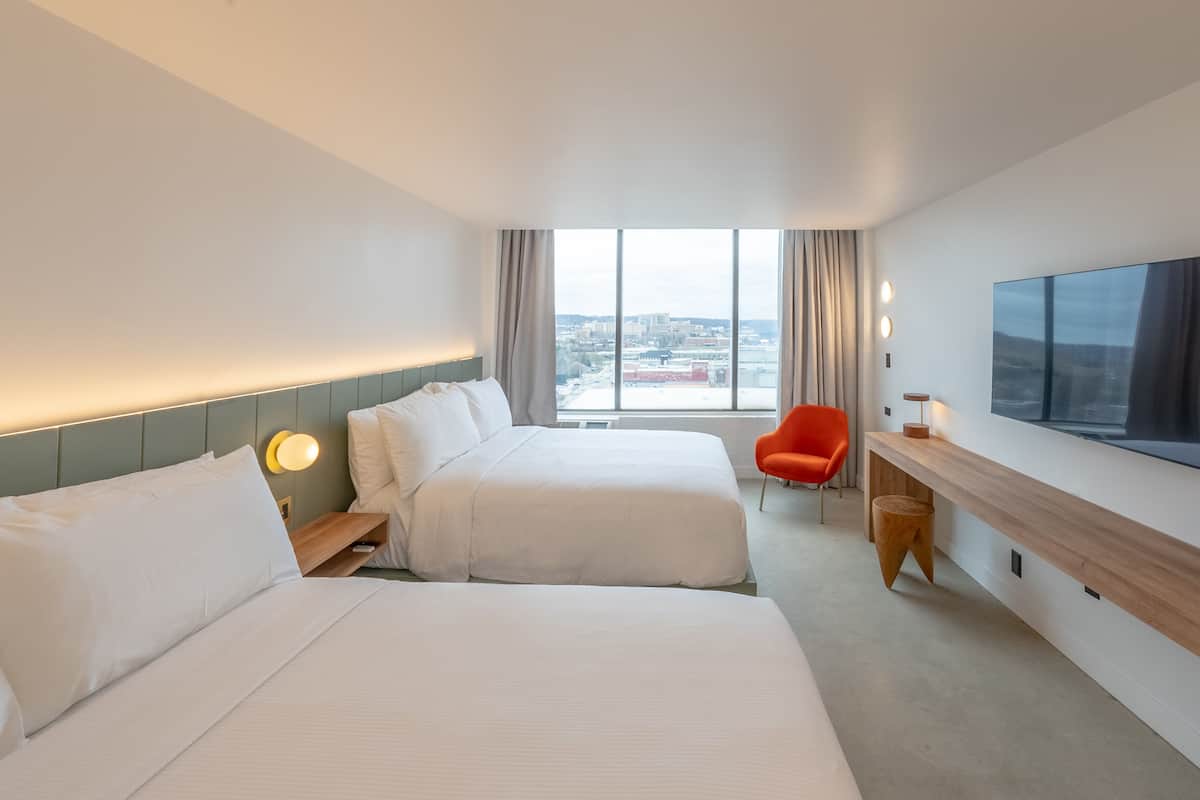 Une chambre d’hôtel avec deux lits, un bureau, une télévision et une vue sur la ville.
