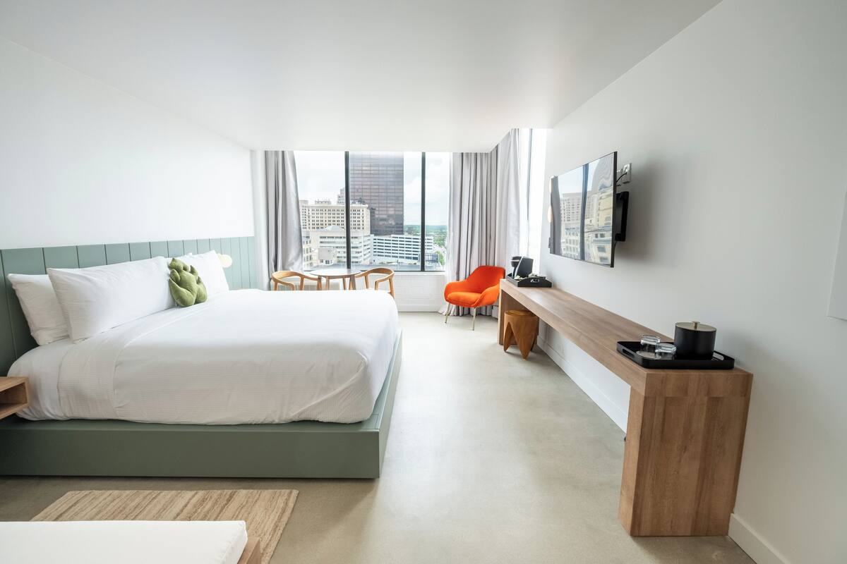Une chambre d’hôtel moderne équipée d’un lit, d’un bureau, d’une chaise et d’un téléviseur.