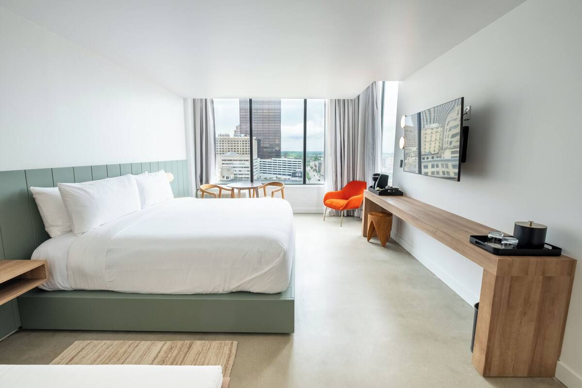 Une chambre d’hôtel moderne équipée d’un grand lit, d’un bureau, d’une chaise et d’un téléviseur fixé au mur.