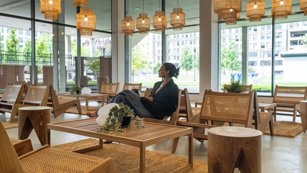 A spacious indoor area with wooden furniture, large windows, and hanging wicker lamps.