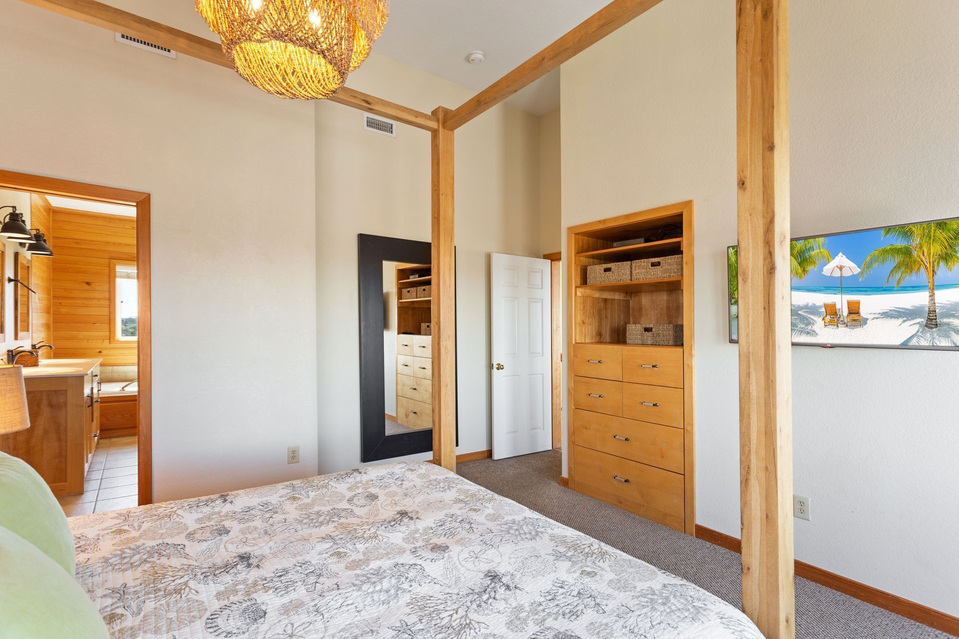 A bedroom with a bed, wooden wardrobe, and a painting of a beach scene.