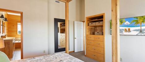 A bedroom with a bed, wooden wardrobe, and a painting of a beach scene.