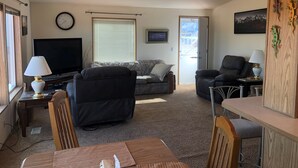 A living room with a sofa, chairs, a TV, a table, and a ceiling fan. - #1 Greenside Oasis (Mattawa)