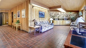 A wooden interior with a sofa, a small table, and a lamp. There is a painting on the wall and a sign that says "EXIT".