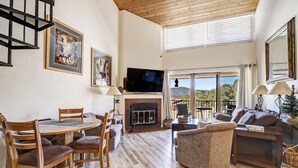 A spacious living room with a fireplace, a television, and a dining area with wooden furniture.
