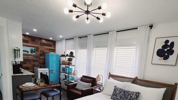 Une chambre moderne avec un grand lit, un bureau et un coin cuisine.