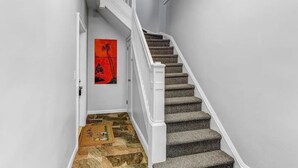 Una escalera con barandilla acolchada y un tapete decorado en la parte inferior.