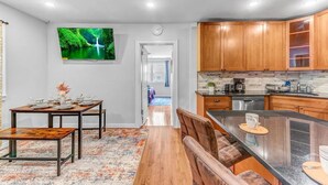 Una cocina moderna con armarios de madera, encimera negra y un comedor con mesa y sillas de madera.
