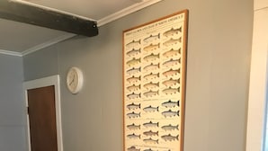 A dining area with a wooden table, chairs, a framed fish illustration, and a clock on the wall. - Cozy convenient home, private access to the Salmon River. (Pulaski)