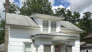 A two-story white house with a chimney, a front porch, and a well-maintained lawn. - Cozy convenient home, private access to the Salmon River. (Pulaski)
