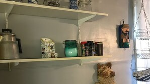 A kitchen with a gas stove, shelves with jars, and a hanging decorative item. - Cozy convenient home, private access to the Salmon River. (Pulaski)