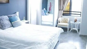 Ein modernes Schlafzimmer mit einem großen Bett, einem kleinen Nachttisch, einem Sessel und einem Fenster mit Vorhängen.