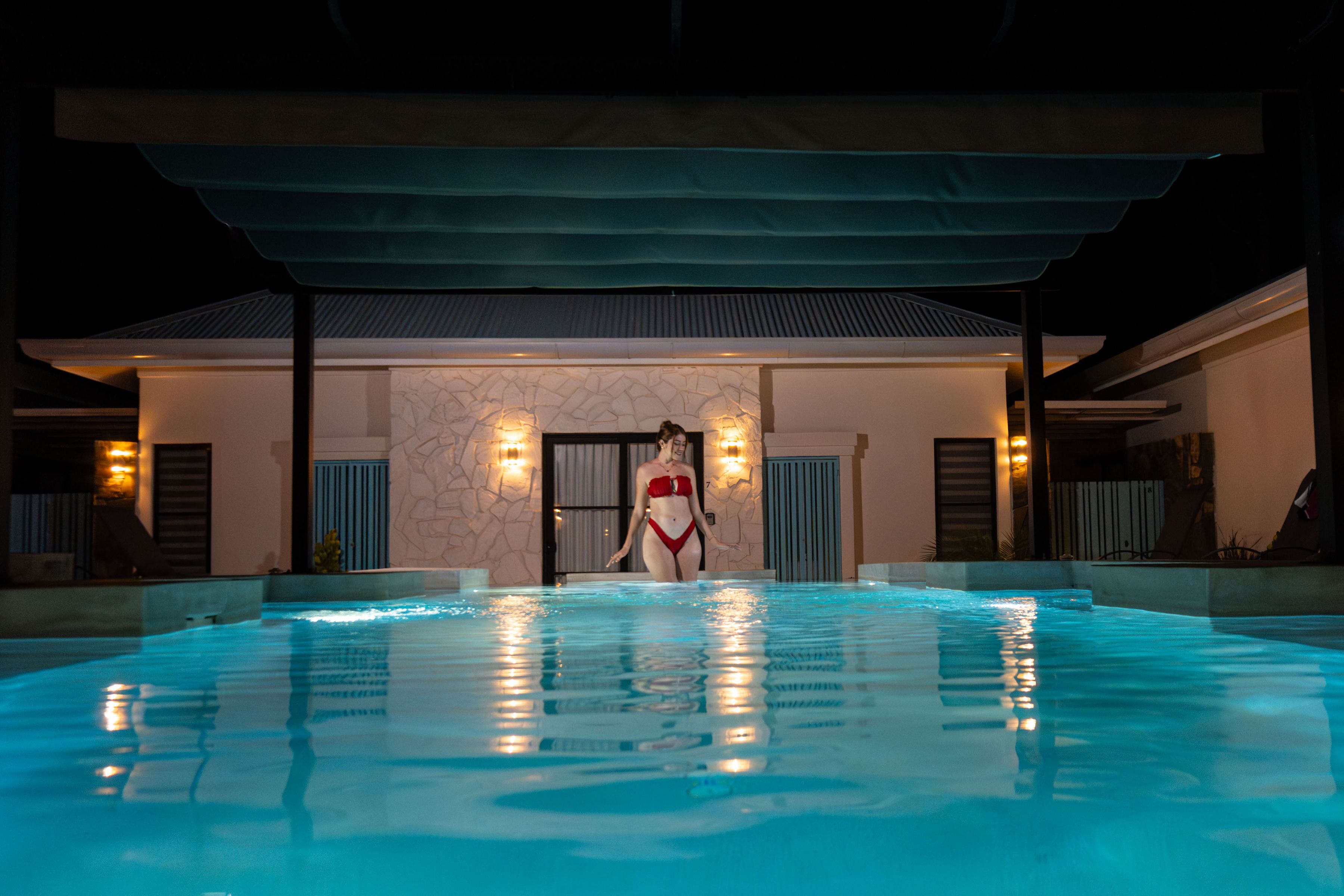 En swimmingpool med en person i en röd bikini som står vid kanten.