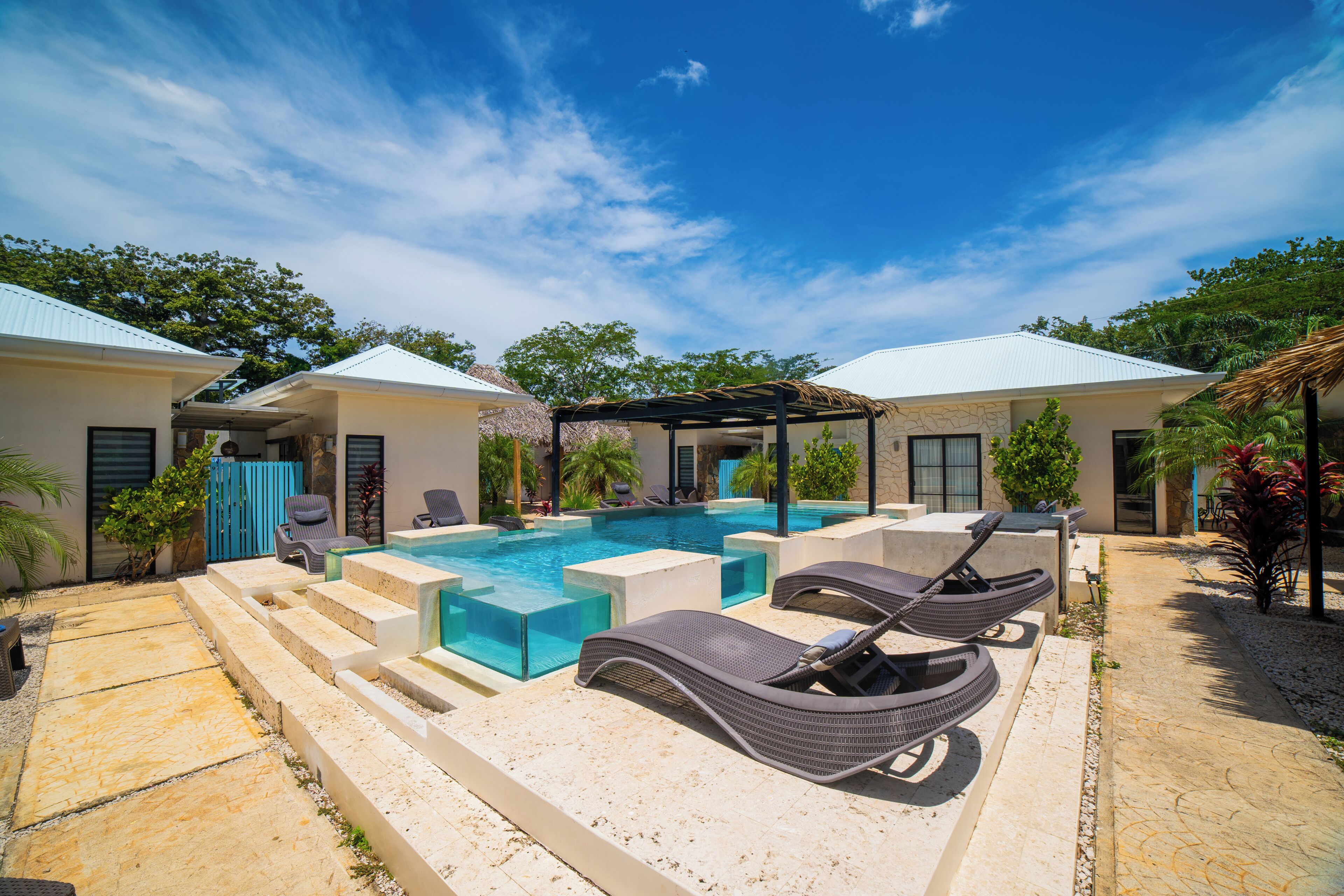 A pool area with lounge chairs and a clear blue sky.