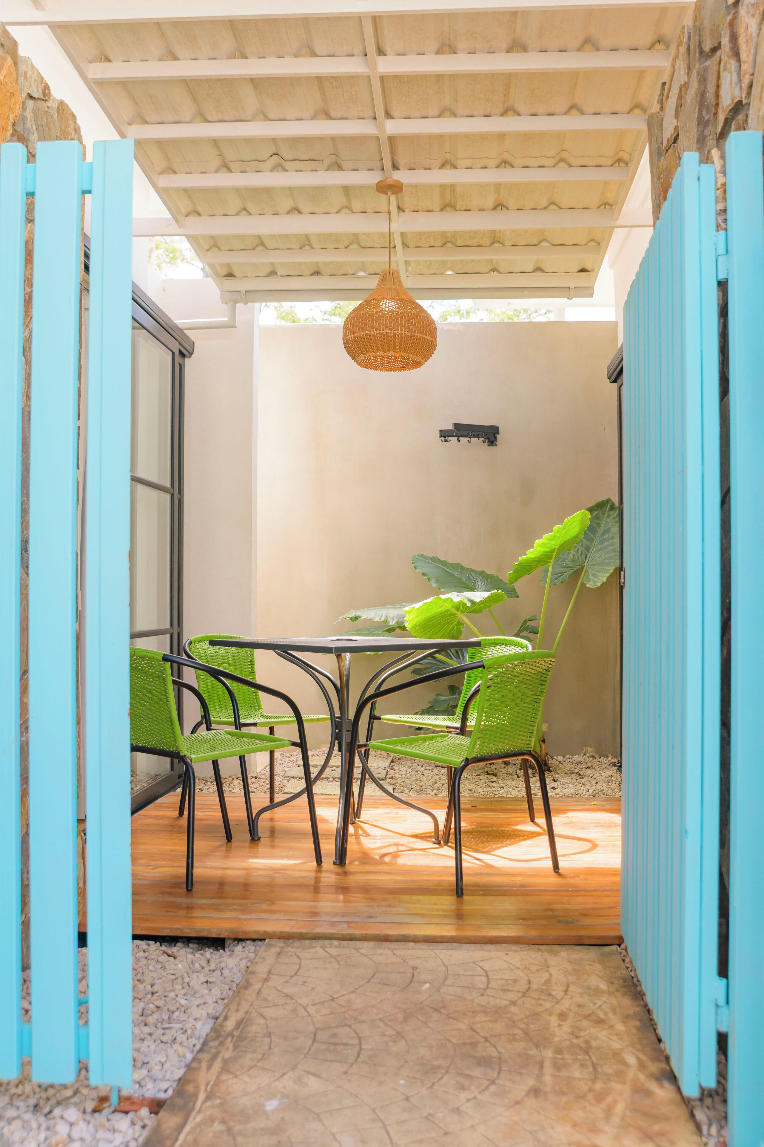 Un patio couvert avec une table et des chaises, un luminaire suspendu et une grande plante.