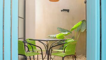 Un patio couvert avec une table et des chaises, un luminaire suspendu et une grande plante.