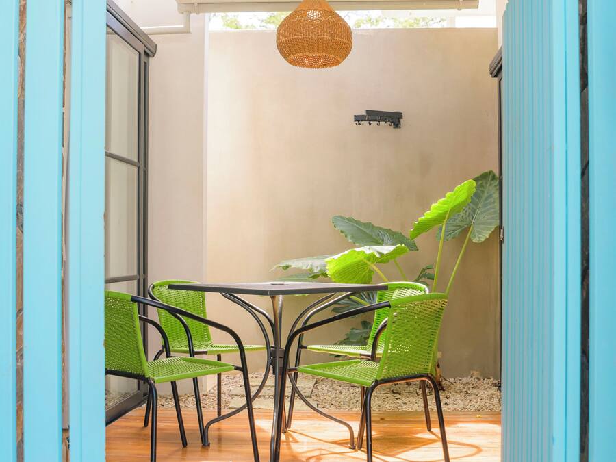 Un patio couvert avec une table et des chaises, un luminaire suspendu et une grande plante.