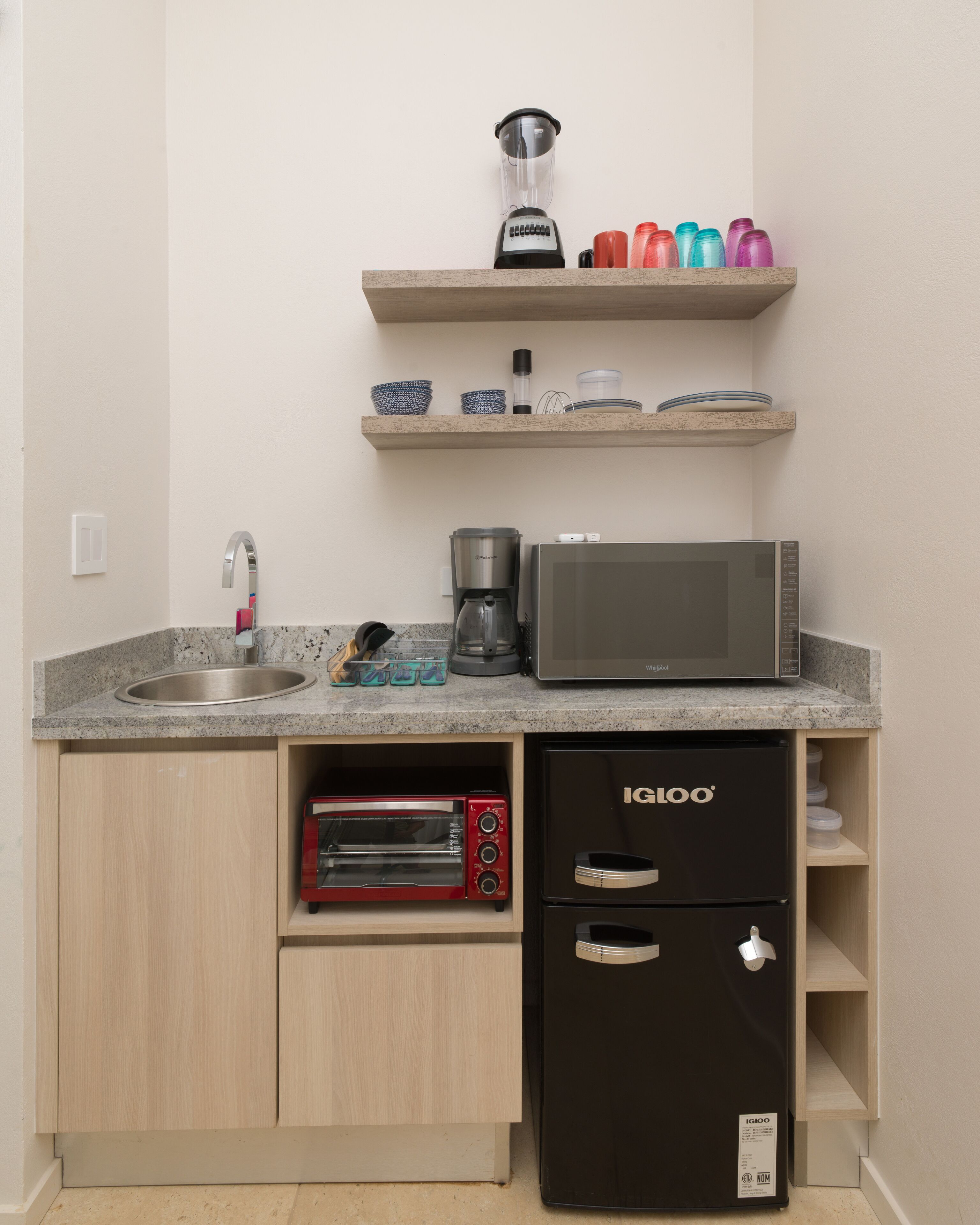 A compact kitchenette with a sink, a microwave, a toaster, and a coffee maker.