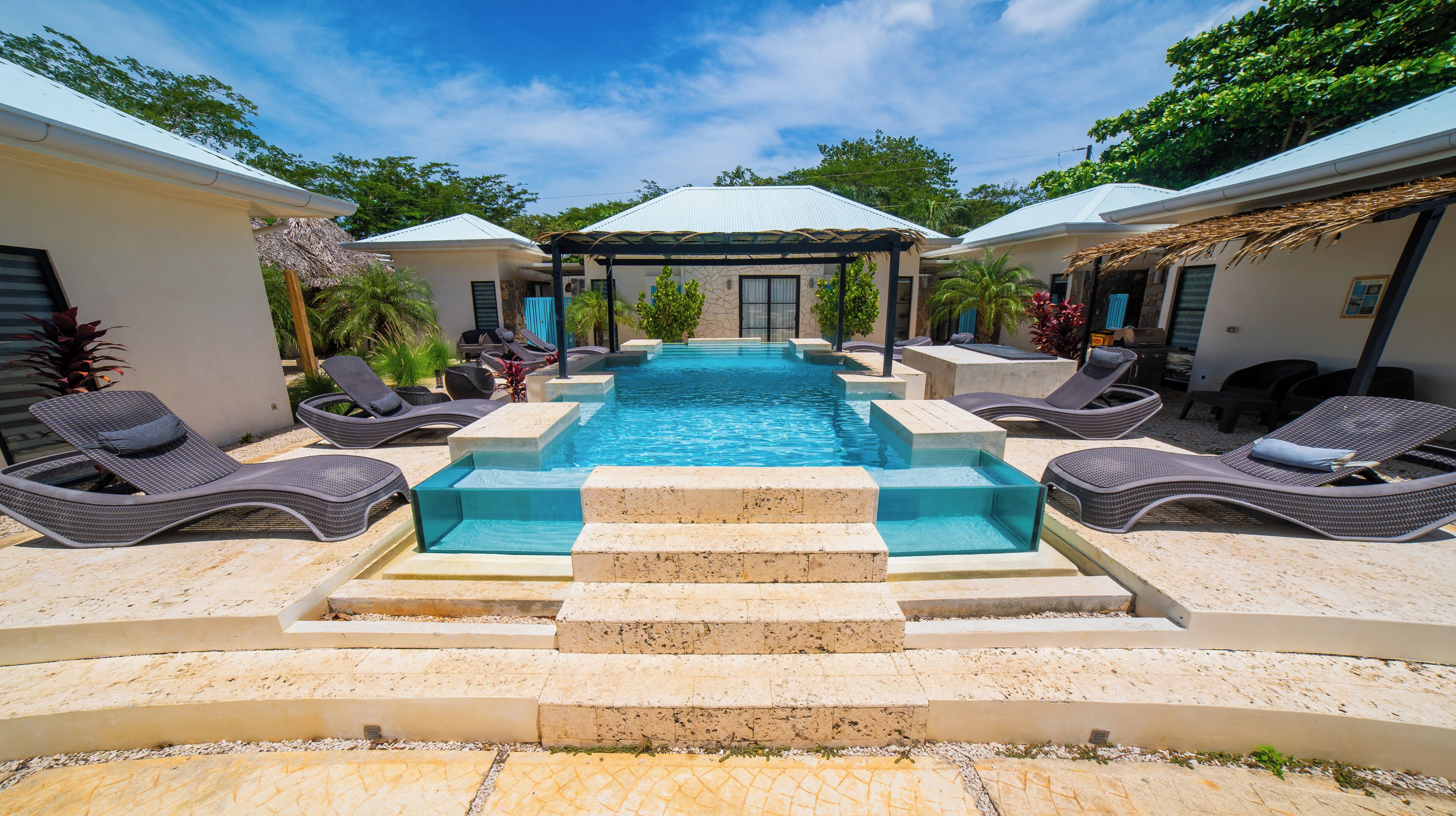 A swimming pool with lounge chairs and a covered area, surrounded by buildings.