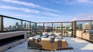 Una terraza en la azotea con vista al horizonte urbano, mobiliario exterior y una zona de barbacoa.